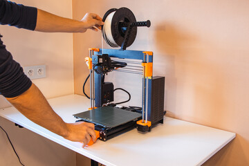 Technological hi-teg tool for making new things. A black and red 3D printer at work. The object is created by laying down continuous layers of material in additive processes.