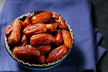 Bowl of pitted dates on a blue linen napkin. Tasty sweet dried dates in bowl. Ramadan food