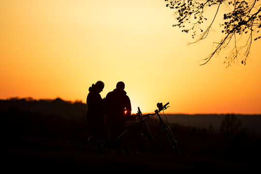 silhouette of a couple sitting on a bicycle in the sunset