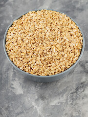 Dry oat flakes in bowl on a gray background. Oat groats flattened into flakes. Top view. Copy space