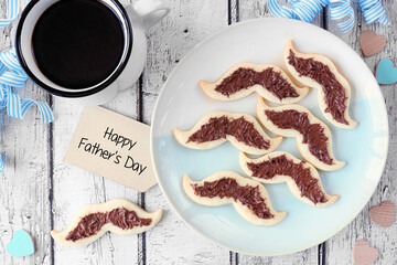 Fun Fathers Day mustache cookies. Above view with coffee and gift tag over a white wood background.