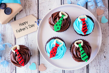 Tasty Fathers Day shirt and tie cupcakes. Above view with gift tag over a white wood background.