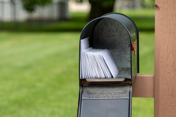 Mailbox full of letters and junk mail. Mail delivery, post office and postal service concept. - obrazy, fototapety, plakaty