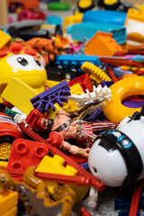 An abundance of toys in the children's room, a lot of plastic multi-colored parts from designers, spare parts for toys, figurines and cubes.