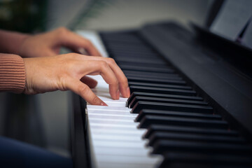 Fototapeta premium Croped Woman hand press key on piano with little finger and blue living room.
