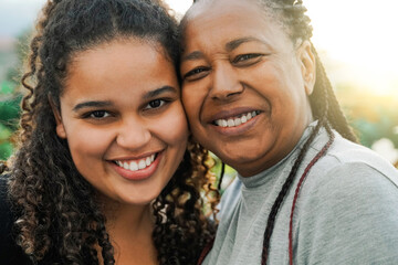 Portrait of happy African mother and daughter having fun outdoor in summer day - Love family concept - Soft focus on senior woman eyes