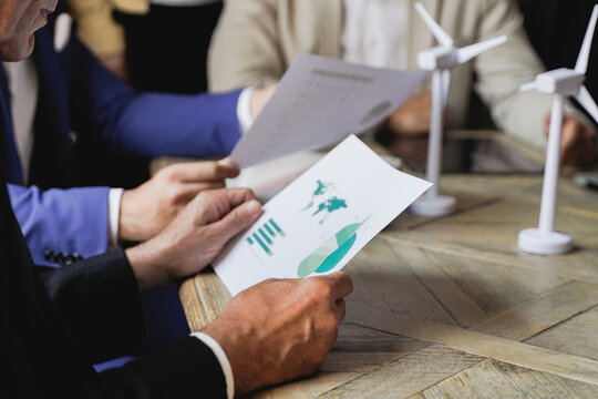 Close-up business people working on sustainable green energy project inside office - Renewable electricity concept