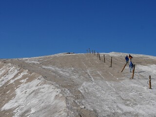 Children walking up a camelle, salt hill in Salins du Midi. Camargue, France.