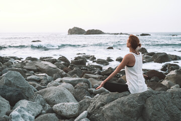 Woman is practicing yoga, meditating on the beach.