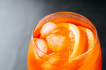 Glass of Aperol Spritz cocktail on a dark background. Aperol spritz cocktail with oranges and ice...