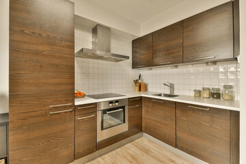 a kitchen with wood cabinets and white tiles on the walls, along with a stainless dishwasher in the corner
