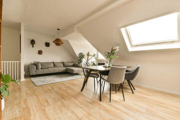 a living room with wood flooring and white walls, including a gray couch in the center of the room