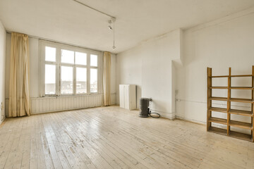 an empty room with wood floors and white walls, there is a ladder leaning on the wall in front of the window