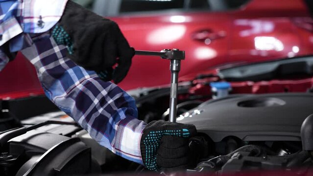 Female auto mechanic unscrewing a nut to replace a car spark plug.