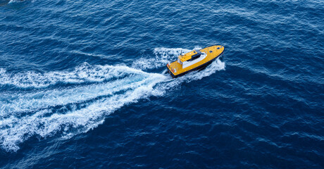 Fototapeta premium Yacht in the sea. Water splash, waves, yellow motorboat for recreation or entertainment, fishing, cruise, swim, nature, ocean.