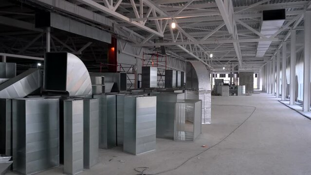 Rectangular galvanized air ducts for the industrial ventilation system stacked in a building under construction.