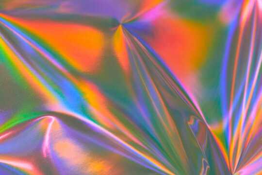 Modern bright neon purple, green, orange colored metallic psychedelic optimistic holographic foil texture. Abstract holographic background 70s, 80s, 90s, 2000s style. Psychedelic groovy retro futurism