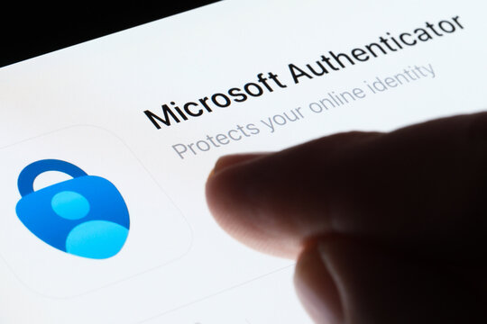 Microsoft Authenticator app seen in App Store on the screen of ipad and blurred finger pointing at it. Selective focus. Stafford, United Kingdom, May 6, 2023