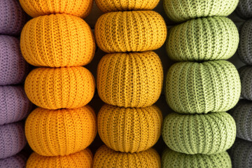 Knitted pumpkins of different colors, crocheted on a light background. Handmade for autumn decor. Halloween and Thanksgiving