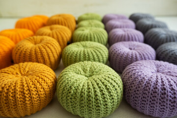 Knitted pumpkins of different colors, crocheted on a light background. Handmade for autumn decor. Halloween and Thanksgiving