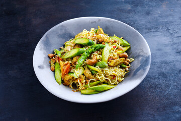 Traditional Thai Pad Mama with Instand noodles, chicken and green asparagus served as a close-up on a design plate with text space