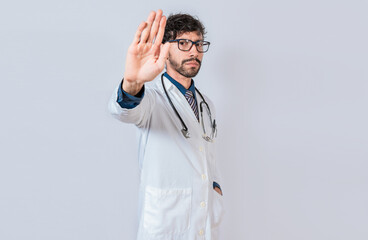 Serious doctor making stop gesture on isolated background, Young doctor making stop gesture with palm of hand