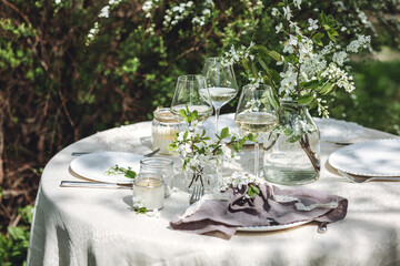 Rustic zero waste wedding decor with natural elements. Fresh spring blooming flowers, candles, linen napkins, wine glasses. Eco friendly decoration for the special holiday dinner. Romantic cozy place