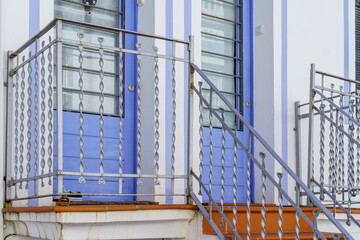An elegant entrance to a modern building, with an intricate blue facade and wooden staircase...