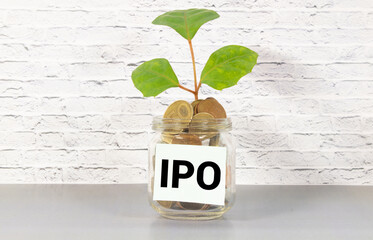 The initial public offering IPO acronym written on a piece of paper. Two piggy banks in the...