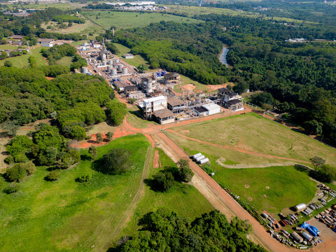 Aerial image of chemical industry. Large structure of pipelines and warehouses with movement of cargo trucks. Industry surrounded by vast vegetation and trees. Located in Brazil, city of Paulínia.