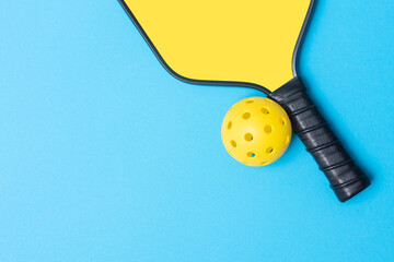 Yellow pickleball racket and ball on blue background. Horizontal education and sport poster, greeting cards, headers, website.