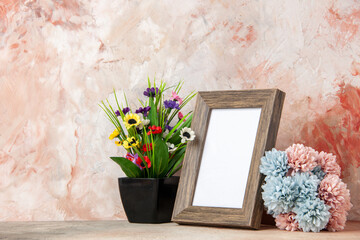 Close up view of dark brown empty wooden photo frame and beautiful flowers on mixed colors background