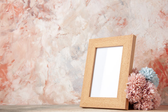 Front close view of light brown empty wooden photo frames and flower on pastel colors background with free space