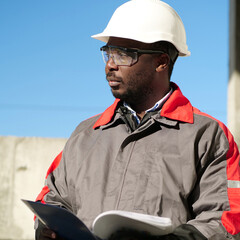 African american worker stands at construction site with work papers