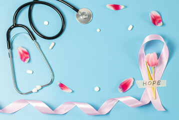 One pink ribbon, tulip, stethoscope and pills on a blue background.