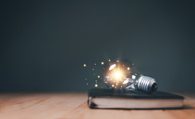Glowing light bulb on a cover of book, Educational knowledge and business education ideas, Innovations, Inspiring from read concept, knowledge and searching for new ideas. Thinking for new idea.