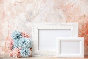 Front view of white small big empty wooden photo frames and flower on pastel colors background with free space