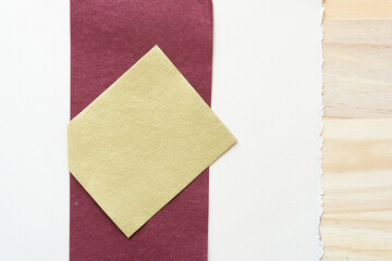 neutral yellow square on oxblood stripe on old art paper texture with deckle edge and wood accent