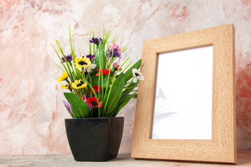 Horizontal view of brown empty wooden photo frame and beautiful flower pot on pastel colors background