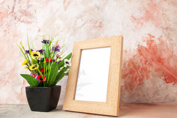 Side view of brown empty wooden photo frame and beautiful flower pot on pastel colors background