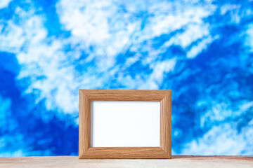 Top view of brown empty picture frame standing on table on abstract blue and white background