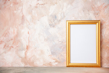 Top view of empty golden photo frame hanging on pastel color wall with free space