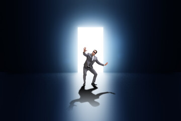 Businessman entering backlit door in escape concept