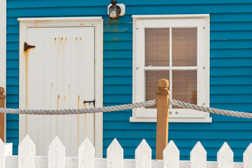 A single white panel wooden door with a vintage metal latch handle in a blue building with a single...