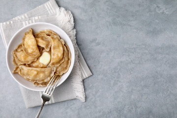 Delicious dumplings (varenyky) with cottage cheese and butter served on light grey table, top view....