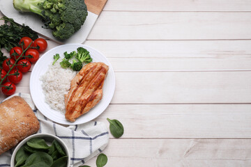 Grilled chicken breast and rice served with vegetables on wooden table, flat lay. Space for text