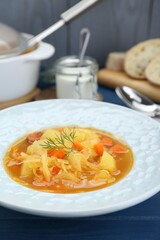 Delicious sauerkraut soup with carrot and dill on blue table, closeup