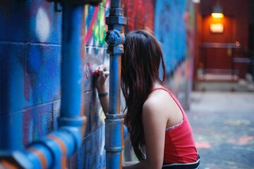 portrait of a woman doing graffiti in an alley © Traysaun
