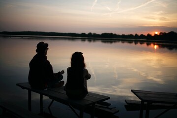 Fototapeta na wymiar friends sitting on a bench meditating and viewing the sunset in a lake 