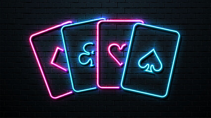 Neon cards of the suit: hearts, diamonds, spades and crosses on the background of a brick wall.